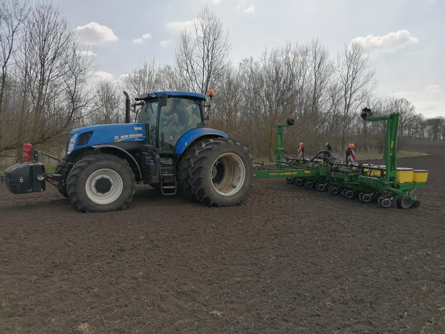 Ezen a képen egy kék traktor látható a szántón